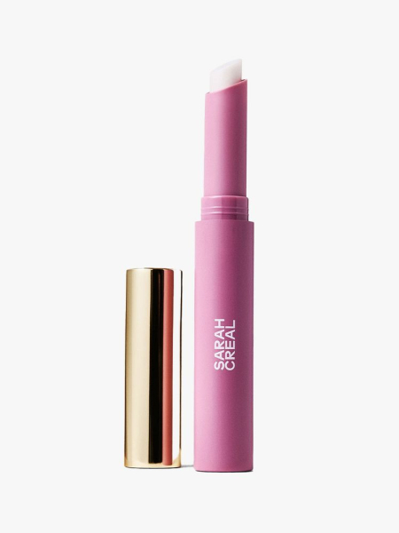 An open pink tube of Sarah Creal Lip Grip Line Filler with a gold cap on a light gray bakcground